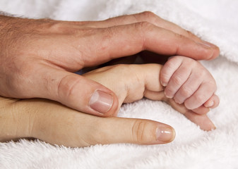 Baby holding hands with mother and father together