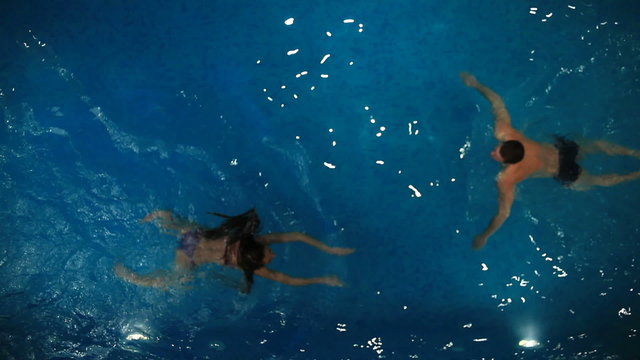 Photo of girl and guy swimming in the pool