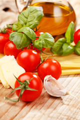 pasta, olive oil and tomatoes on the wood background