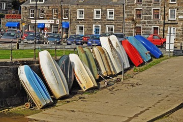 Many colourful  rowing boats upended in the harbour of picturesque Porthmadog in Wales 