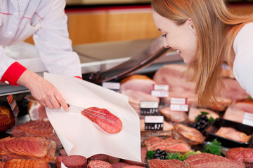 verkäuferin zeigt scheiben salami