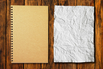 notebook with crumpled paper on wood background