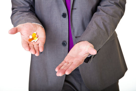 Man in suit holding pills isolated on white