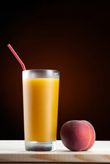 Fresh peach juce in glass on dark background