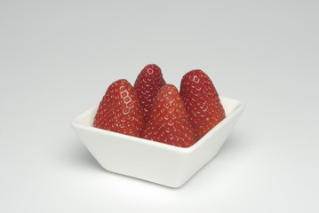 Cuatro fresas en  un cuenco blanco