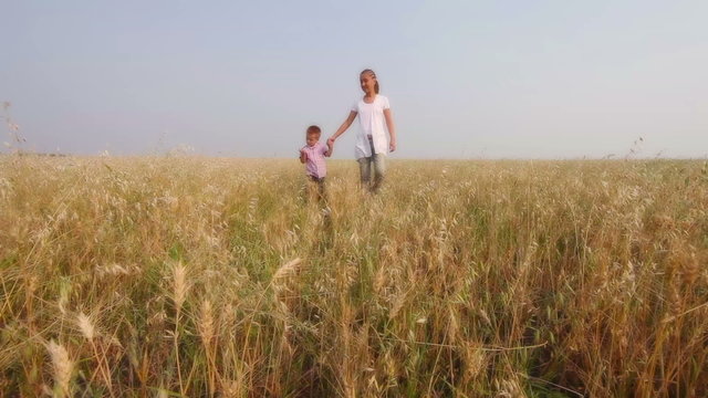 A young woman with her little son walking along the meadow