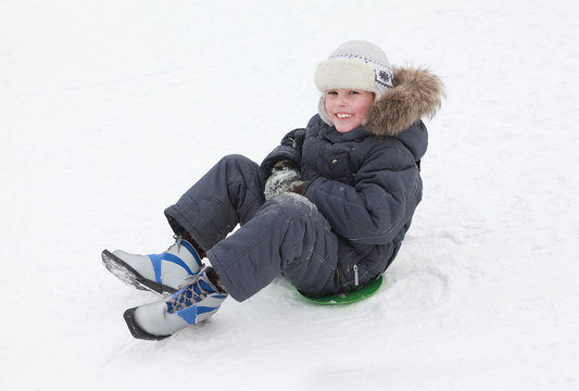 smiling boy skates on green ice-boat on pure white snow