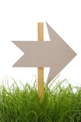 cardboard direction sign on green grass