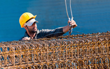 Construction worker loading stack of reinforcement beam cages to - 31510476