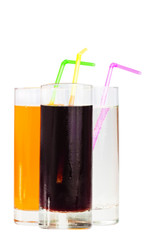 Three highball glasses of soda with drinking straws on a white b