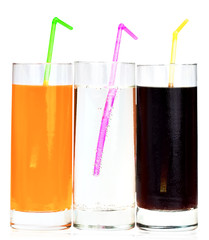 Three highball glasses of soda with drinking straws on a white b
