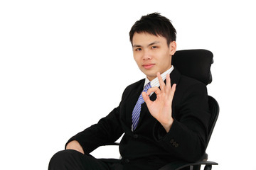 An executive showing the OK sign while sitting on a chair