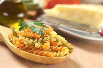 Colorful raw fusili pasta on wooden spoon