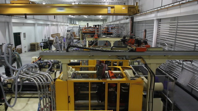 A crane shot of a robotics factory with multiple moving parts

