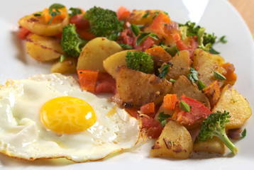 Fried egg with fried potatoes, broccoli, carrot, tomato, onion