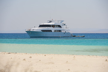 Fototapeta na wymiar Large motor yacht moored off a tropical beach