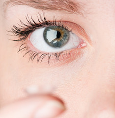 Fototapeta premium Close up of inserting a contact lens in female eye