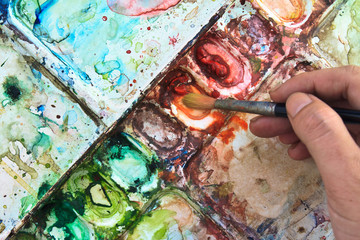 Watercolor palette with paintbrush in hand