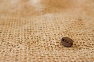 Single coffee bean on burlap sack background