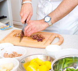 Chef cutting the olives on a wooden board