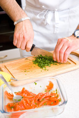Chef cutting the parsley on a wooden board
