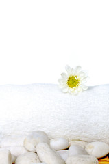 Fototapeta na wymiar Beautiful flower on white towel and stones on the bamboo mat.