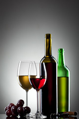Red and white wine in glasses with grape and bottles