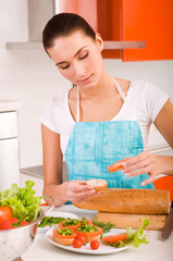 Obraz na płótnie Canvas Attractive smiling woman preparing fresh healthy sandwiches in h
