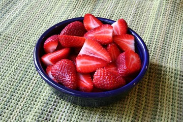 Strawberries in  a blue bowl on a green background