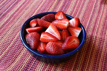 Strawberries in  a blue bowl on a red background