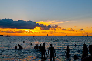 Silhouettes of people in the sea at sunset