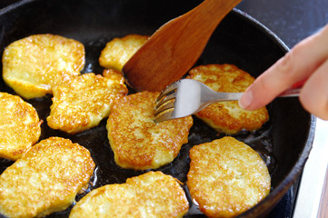 potato pancakes frizzle in black frying pan