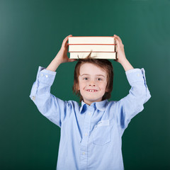 kleines schulkind balanciert bücher auf dem kopf