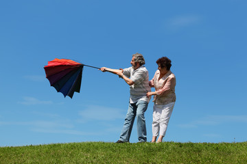 woman and man standing on summer lawn with umbrella