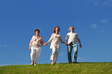 adult daughter and her parents holding for hands and walking