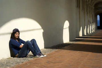 Sad girl sitting against a wall