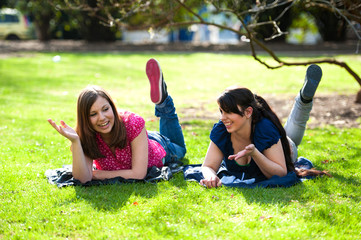 Two young females relaxing  in a park