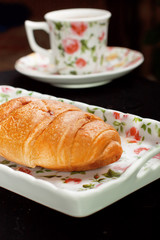 croissant on the plate with tea cup