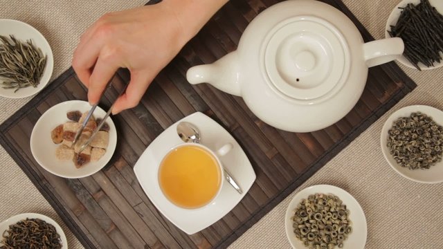 Woman adds brown sugar in cup of tea