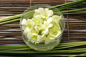 bowl of orchid and thin bamboo on mat
