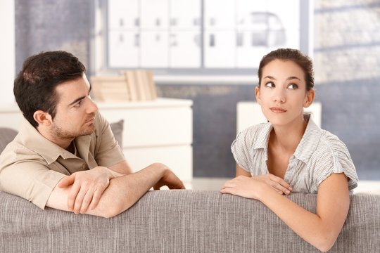Young couple sitting on sofa in bad mood