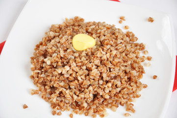 Appetizing crumbly buckwheat with butter on white background