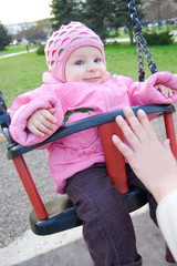 Baby girl in pink on swing