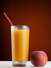 Fresh peach juce in glass on dark background