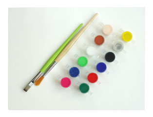 Naklejka premium Colourful paints with brush kept on painting sheets