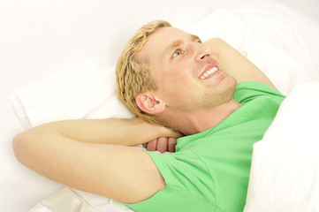 Cheerful young guy waking up in morning on bed
