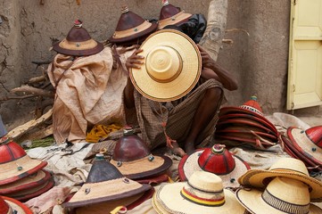 An African hat seller covering his face with a hat