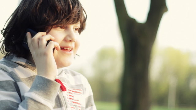 Young smiling boy talking on mobile phone, outdoors