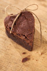 chocolate brownie heart with bow, rough wooden background