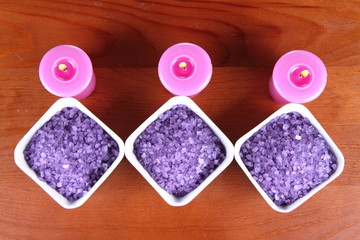 Lavender spa salt and lavender candles on a wooden background